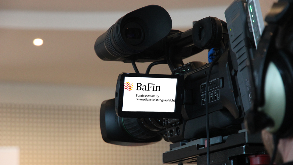 Abbildung zeigt eine Kamera mit einem Miniaturbildschirm, auf dem das BaFin-Logo zu sehen ist, aus der Perspektive hinter dem/der Aufzeichnenden.